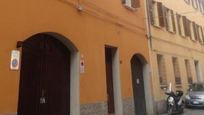 A multi-story building with a yellow facade, multiple windows with shutters, and a dark brown entrance door. - B&B Chez Moi (Bologna)