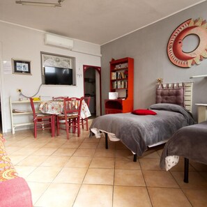 A bedroom with a bed, a desk with a chair, a bookshelf, and a TV. - For Ever (Fiumicino)