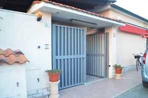 A gated entrance with a blue gate, a tiled roof, and a parked car. - For Ever (Fiumicino)