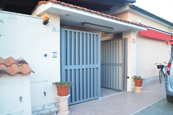 A gated entrance with a blue gate, a tiled roof, and a parked car. - For Ever (Fiumicino)