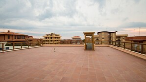 A rooftop terrace with a tiled floor, a small kiosk, and surrounding buildings.