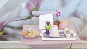 A table set with a plate of pastries, a teapot, a cup, and a small potted plant.