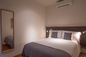 A bedroom with a bed, bedside lamps, a mirror, and an air conditioning unit. - Feel Porto Codeçal Apartments (Porto)