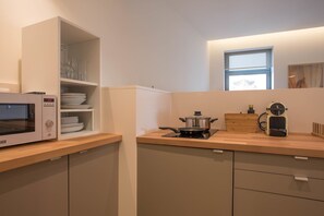 A compact kitchen with a microwave, a stove, and a coffee maker. - Feel Porto Codeçal Apartments (Porto)
