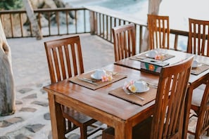 A wooden dining table set with placemats, cutlery, and a floral centerpiece. - The Villa Dini Dnusa Lembongan (Lembongan Island)
