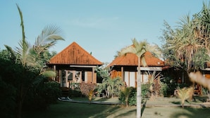 A resort with two thatched-roof cottages surrounded by lush tropical vegetation. - The Villa Dini Dnusa Lembongan (Lembongan Island)