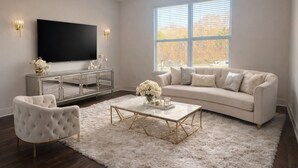 A modern living room with a large flat-screen TV, a sofa, a coffee table, and a decorative cabinet.