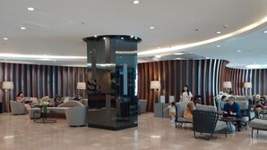 En rummelig lobby med en central søjle, siddepladser og en reception.