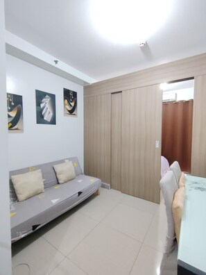 Quarto com sofá, mesa de jantar e porta deslizante.