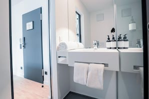 Ein modernes Badezimmer mit einem weißen Waschbecken, zwei Handtuchhaltern und einem Spiegel.