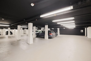 Eine mehrstöckige Tiefgarage mit weißen Säulen und Neonbeleuchtung.