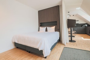 Ein modernes Schlafzimmer mit Bett, Schreibtisch und einer Küchenzeile.