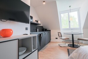 Eine moderne Küche mit schwarzem Arbeitsplatz, einer weißen Schüssel und einer Kaffeemaschine. Es gibt einen Essbereich mit einem runden Tisch und Stühlen.