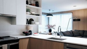 Een moderne keuken met een centraal eiland, inbouwplanken, een eethoek en een donkergrijze bank.