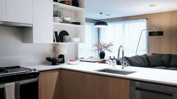 A modern kitchen with a central island, built-in shelves, a dining area, and a dark-colored sofa.
