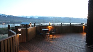 Un pontile in legno con tavolo e sedie, con vista su un paesaggio montuoso.