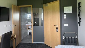 Hotelkamer met een bed, een bureau, een stoel, een televisie, een badkamer met douche en toilet.