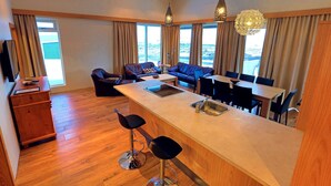 A modern hotel room with a large dining area, a sofa set, and a bar area. - Hrimland (Akureyri)