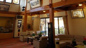Een traditionele Japanse kamer met tatami vloerbedekking, een shoji scherm en een grote hanglamp.