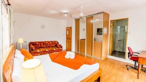 Een hotelkamer met een bed, een bank, een bureau en een douche.