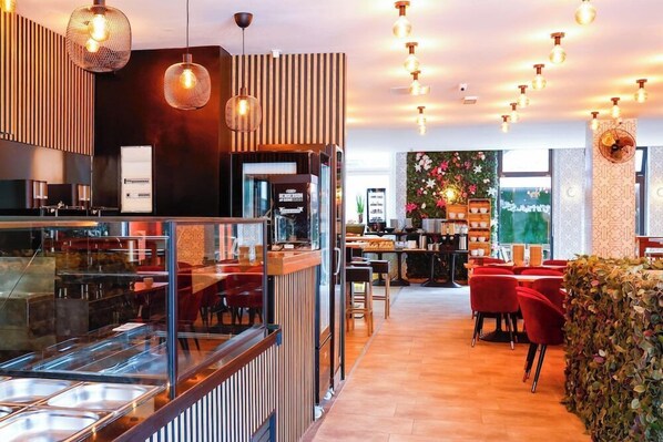 Ein modernes Restaurant mit einer Buffet-Ecke, Holzvertäfelung und roten Stühlen.