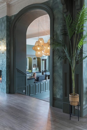 A lobby with a large arched doorway leading to a bar area, a hanging light fixture, and a potted plant. - Lincombe Hall Hotel (Torquay)