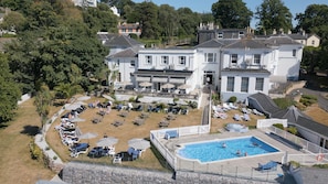 A large white building with a swimming pool and sun loungers. - Lincombe Hall Hotel (Torquay)
