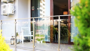 A modern building with a glass balcony, outdoor seating, and a view of the cityscape. - Jessapart Hotel - Triton Park (Warsaw)