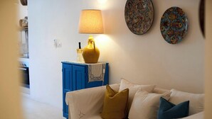 Un salon avec un canapé blanc, un meuble bleu et une lampe jaune.