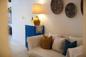 Un soggiorno con un divano bianco, un mobile blu e una lampada gialla.