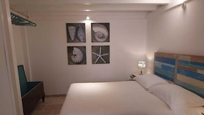 Une chambre à coucher comprenant un lit, une table de chevet, une lampe fixée au mur et quatre tableaux encadrés.