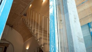 Un escalier avec des balustres blanches et une main courante en bois, menant à l’étage supérieur.