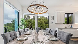 Comedor con una mesa de madera dispuesta para seis personas, rodeada de sillas tapizadas de color gris.