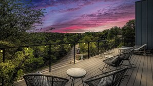 Una terraza con asientos al aire libre, rodeada de árboles y vistas al cielo.