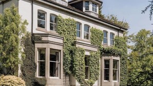 Une grande maison à deux étages, dotée d’une imposante baie vitrée et d’un porche abrité.