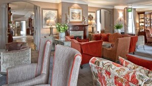 Un vaste espace de vie offrant de nombreuses possibilités d’assise, notamment des fauteuils et des canapés, une cheminée et une table basse.