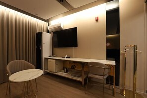 Hotelkamer met een bureau, een stoel, een televisie, een airconditioning en een kledingkast.