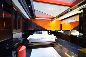Een moderne hotelkamer met een groot bed, een kaptafel met spiegel, en een rode accentmuur.