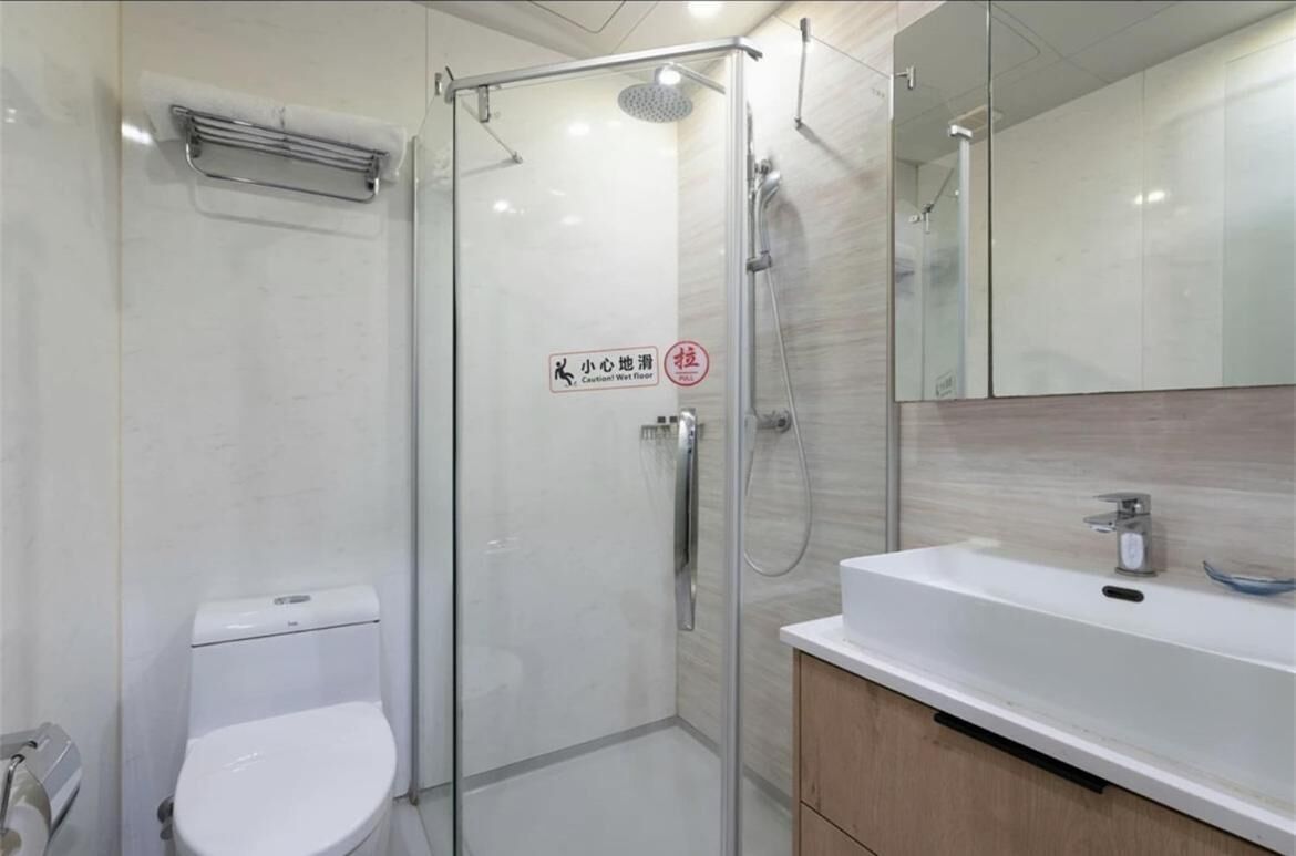 A modern bathroom with a glass-enclosed shower, a white toilet, and a sink with a mirror above it.