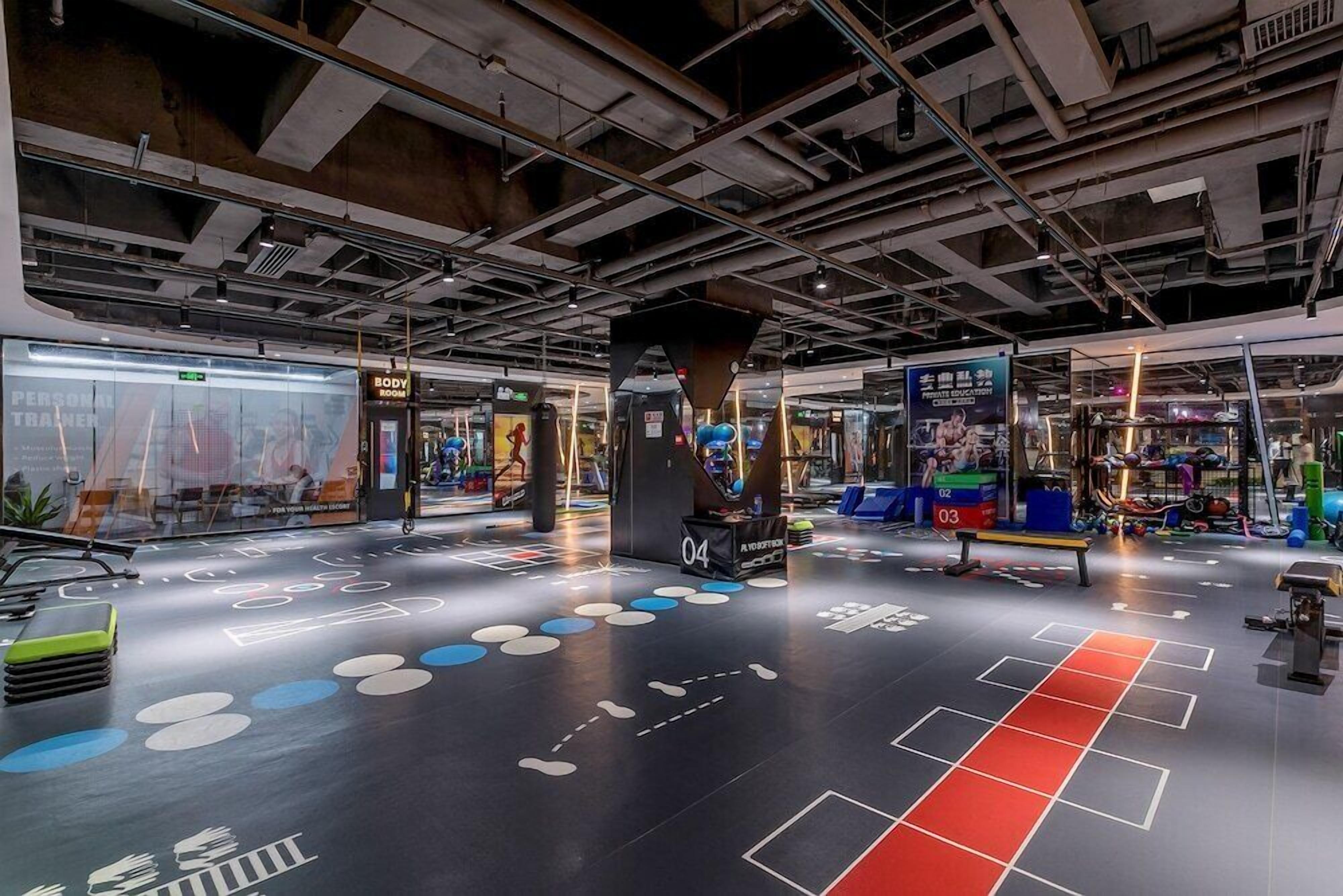 A gym with various exercise equipment, a mirrored wall, and a floor with geometric patterns.