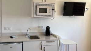 A compact kitchen with a microwave, coffee maker, and dishwasher. - Hospedería Almundo (Tarifa)