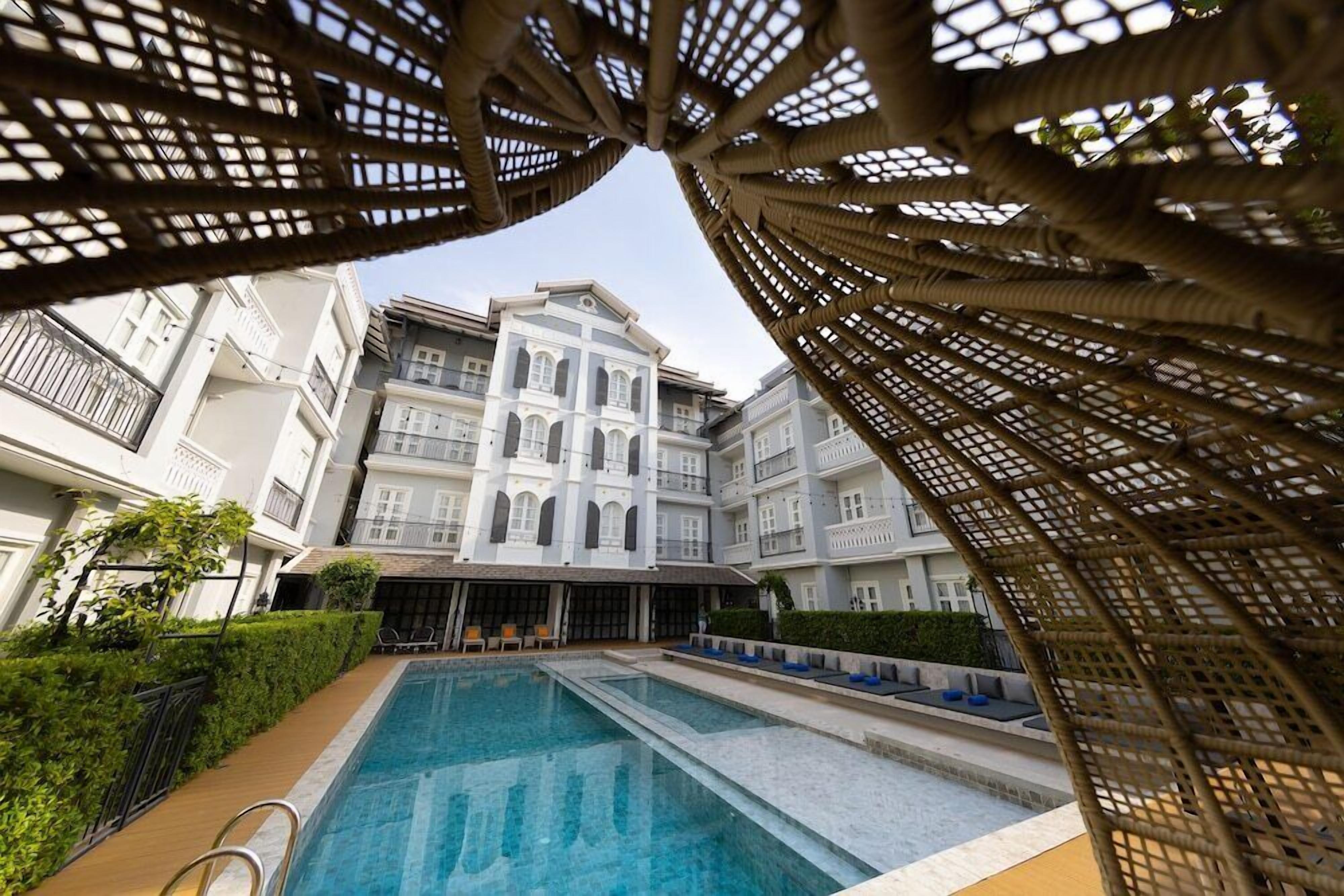 A pool area with a clear view of a multi-story building with balconies and a central entrance.