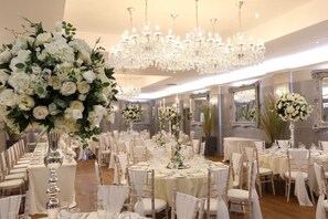 A banquet hall with round tables, white chairs, and chandeliers. - The Crown Hotel (Doncaster)