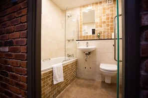 A bathroom with a glass shower enclosure, a white bathtub, a sink, and a toilet. - The Crown Hotel (Doncaster)