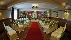 A formal event space with rows of white chairs, a red carpet, and floral decorations. - The Crown Hotel (Doncaster)