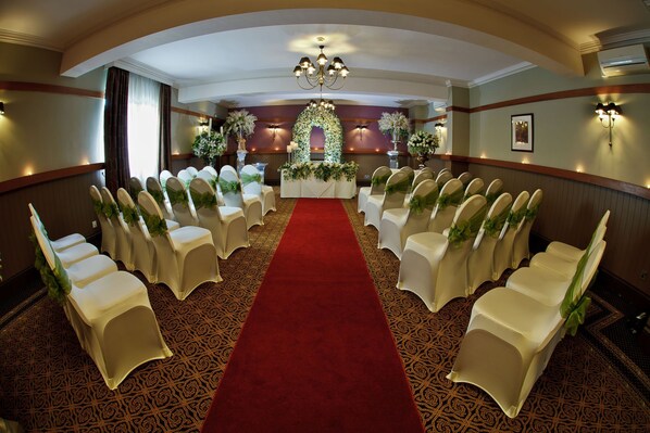 A formal event space with rows of white chairs, a red carpet, and floral decorations. - The Crown Hotel (Doncaster)