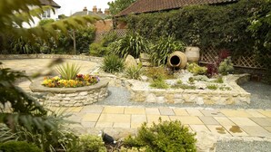 A garden with stone planters, a small water feature, and a variety of plants. - The Crown Hotel (Doncaster)