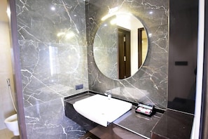 A modern bathroom with a marble vanity, a round mirror, and a white sink.