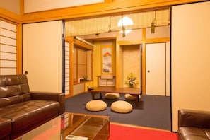 Ett traditionellt japanskt rum med tatamimattor på golvet, ett lågt bord och kuddar.