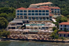 A multi-story hotel with a pool area, outdoor seating, and a view of the sea. - Tsamis Zante Suites (Zakynthos)